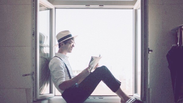 窓辺で本を読む男性
